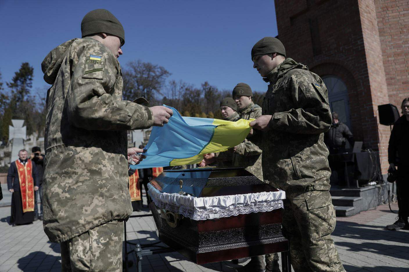 Soldati ucraini mentre collocano la bandiera nazionale sulla bara di un loro ufficiale caduto pochi giorni fa nei combattimenti