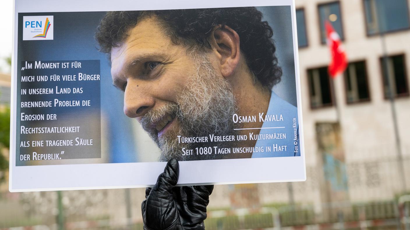 Un manifestante alza la foto di Osman Kavala in segno di protesta a Berlino (foto d'archivio)