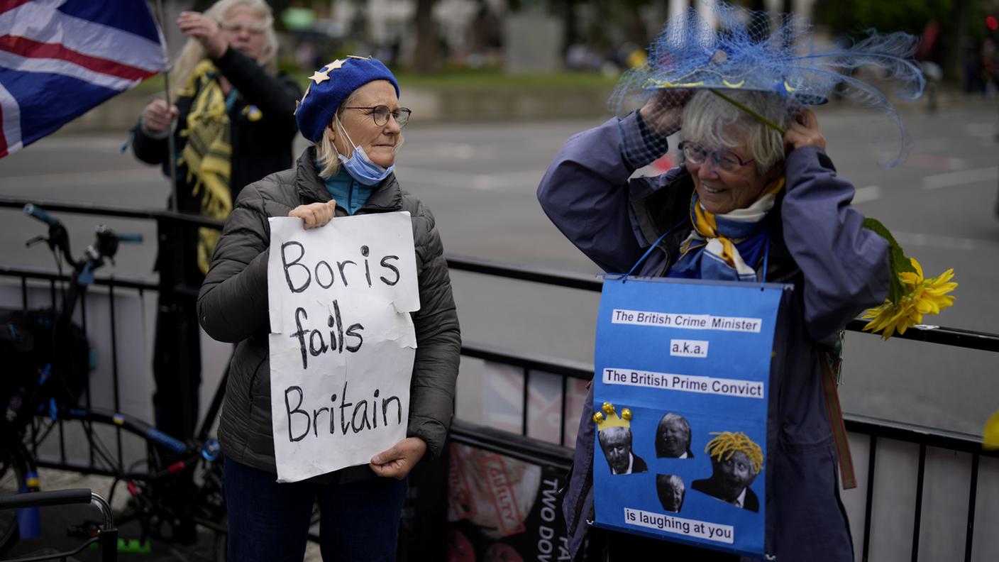 Alcuni oppositori di Boris Johnson con cartelli di protesta all'esterno della sede del Parlamento