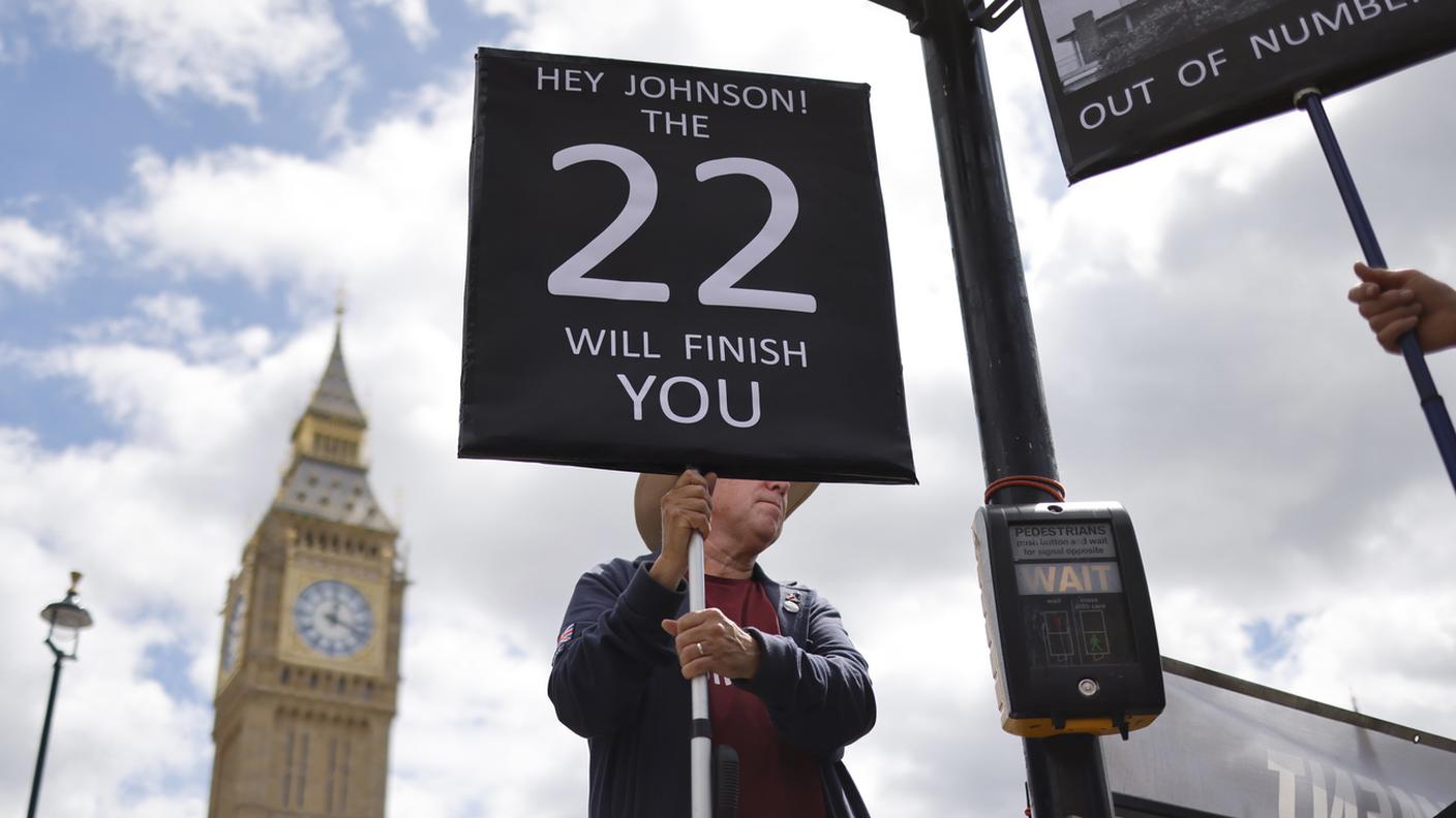 Un uomo protesta contro Boris Johnson fuori dal Parlamento a Londra