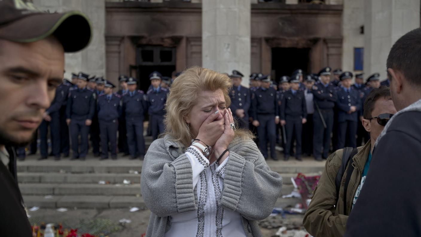 Una donna scoppia in lacrime davanti al palazzo bruciato venerdì