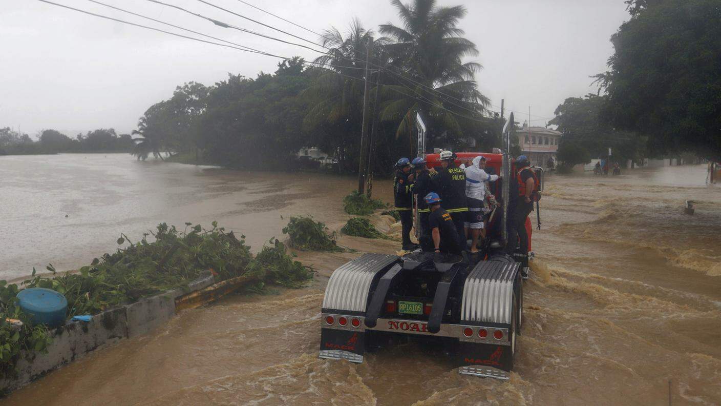 Varie persone sfuggono alle inondazioni salendo su un camion a Puerto Rico