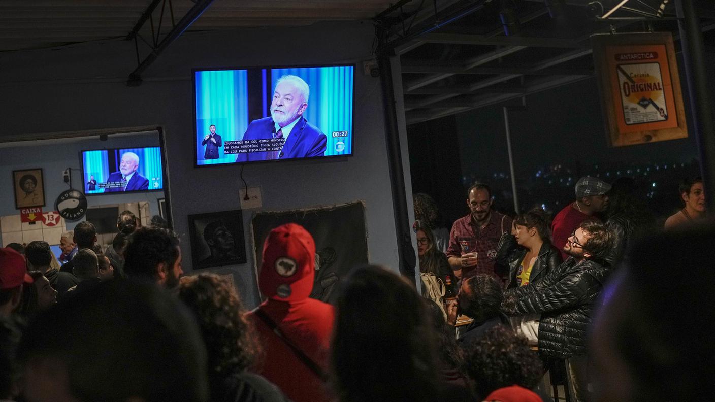 Decine di brasiliani seguono il dibattito tra Lula e Bolsonaro di giovedì in un locale pubblico