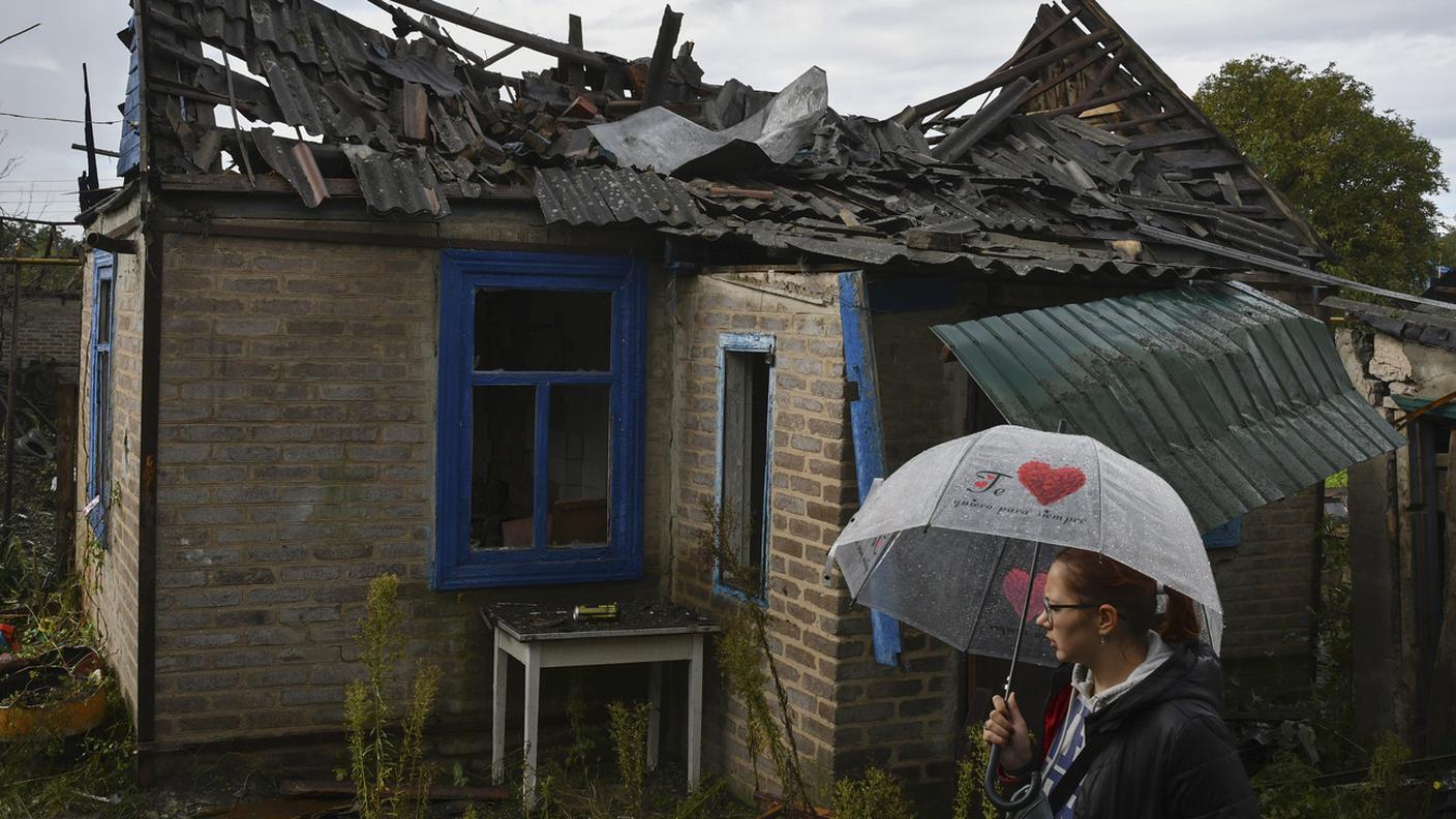 Una ragazza cammina a fianco di quanto resta della sua casa distrutta nell'Oblast di Kharkiv