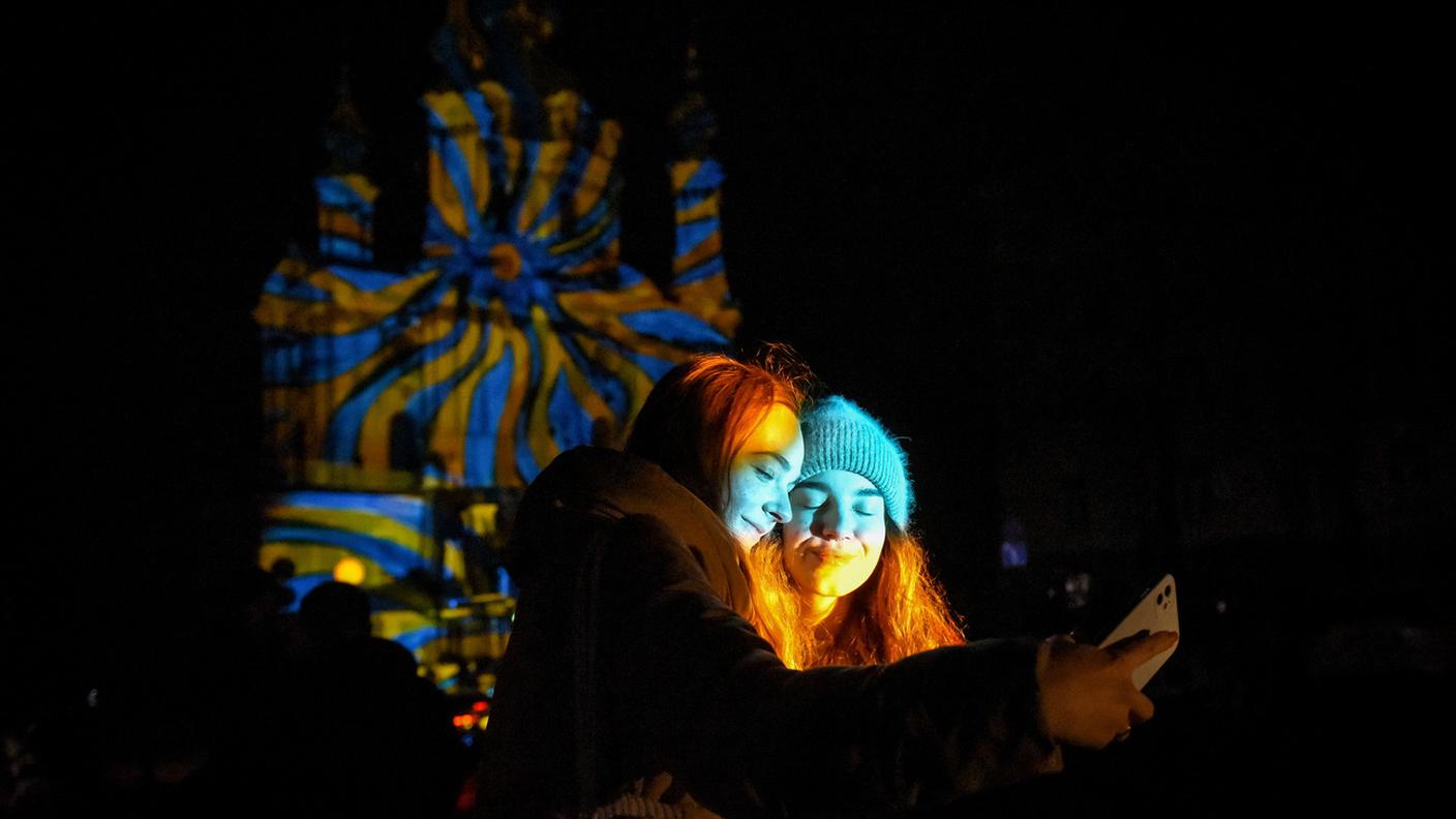 Due ragazze ucraine si fanno un selfie con la chiesa di Sant'Andrea a Kiev illuminata sullo sfondo