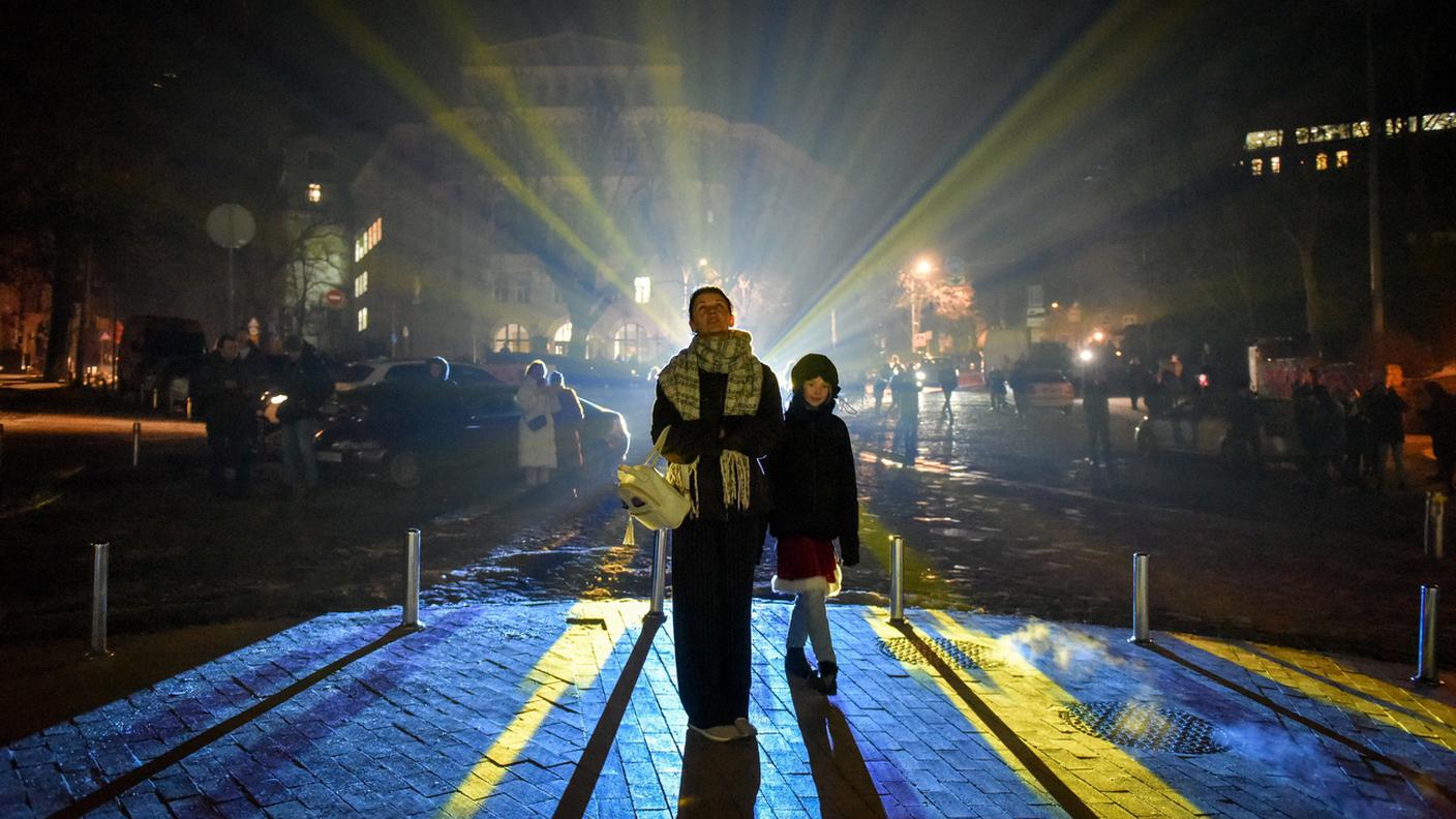 La gente guarda la chiesa di Sant'Andrea di Kiev illuminata dall'artista svizzero Gerry Hofstetter