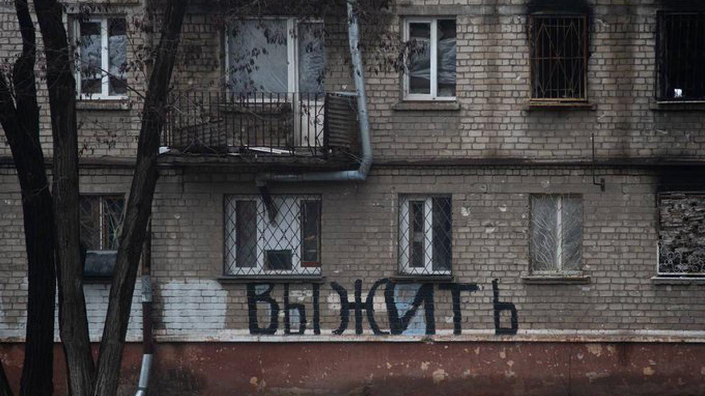 La scritta "sopravvivere" sul muro di una palazzina a Mariupol il giorno di Natale