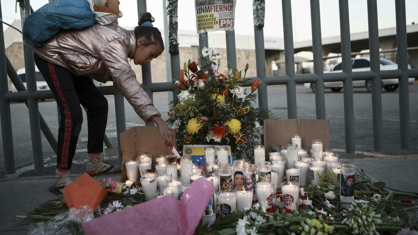 Una ragazza accende una candela a ricordo dei migranti morti nella strage di Ciudad Juarez
