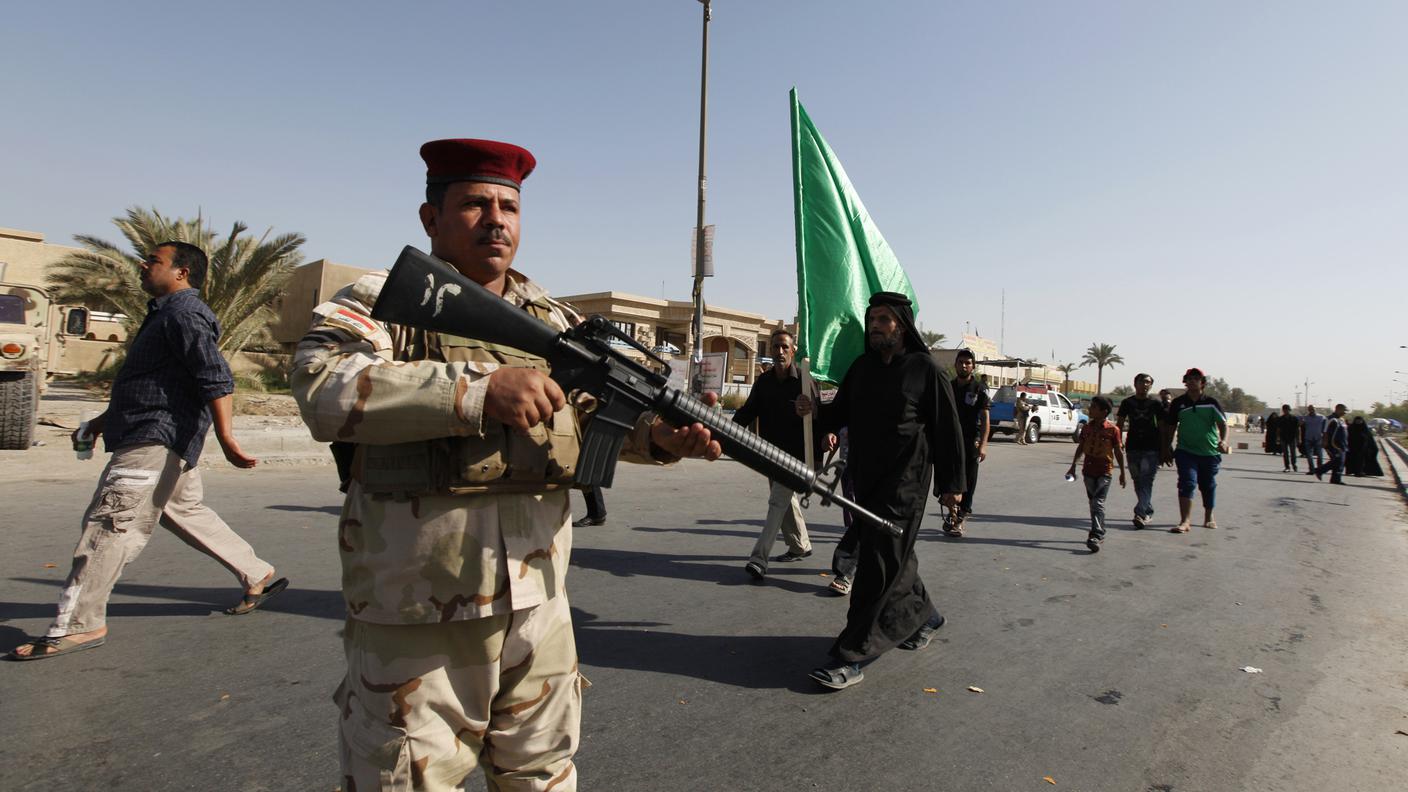 Un soldato scorta un gruppo di pellegrini sciiti, vittime di diversi attentati quetso fine settimana in Iraq