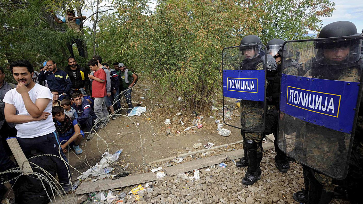 Agenti delle forze speciali macedoni controllano un gruppo di rifugiati