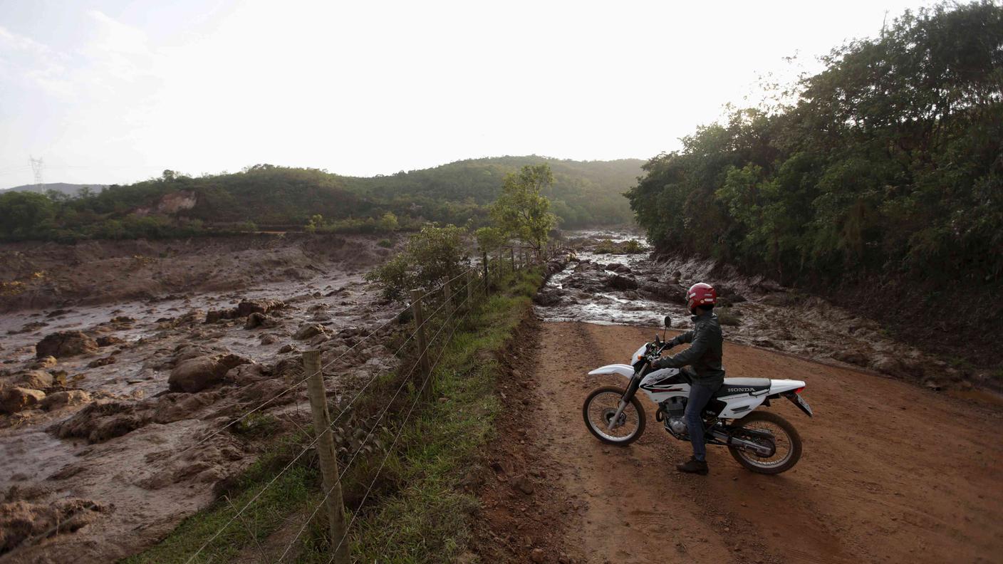 Un motociclista osserva la colata di fango muoversi presso Mariana