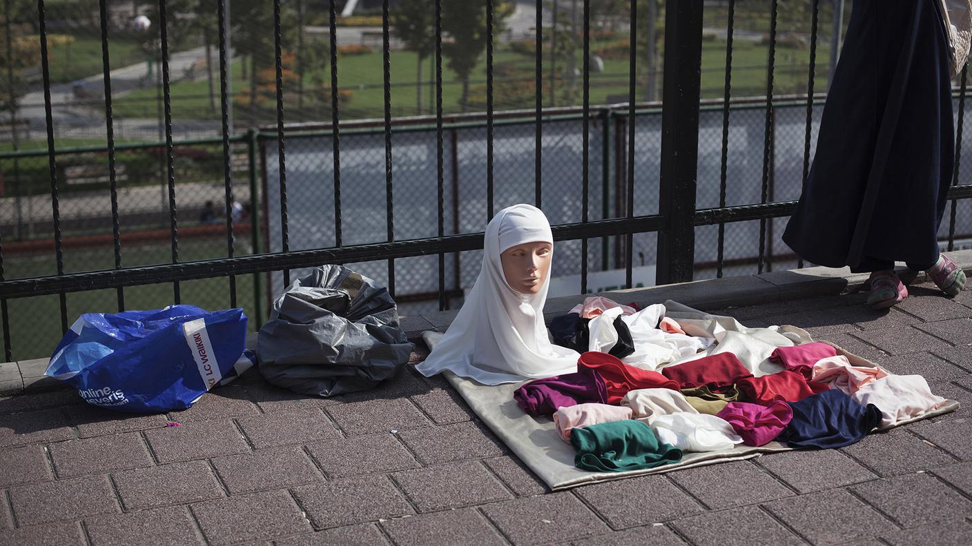 Ragazza senza testa. Nel quartiere conservatore di Fatih una giovane vende per strada i tradizionali veli islamici. Istanbul, il 31 Agosto 2016.