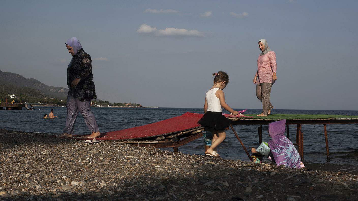 Alcune donne turche con il costume da bagno coperto (cosiddetto burqini) stanno tornando alla spiaggia dopo una nuotata. Assos / Ayvacık / Çanakkale, Turchia occidentale, il 12 agosto 2016
