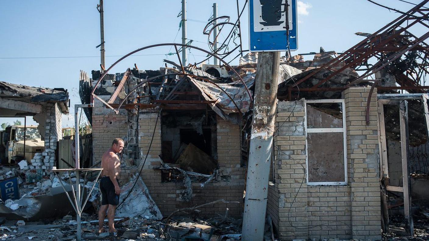 Un uomo guarda quel che resta di una casa nell'est dell'Ucraina 