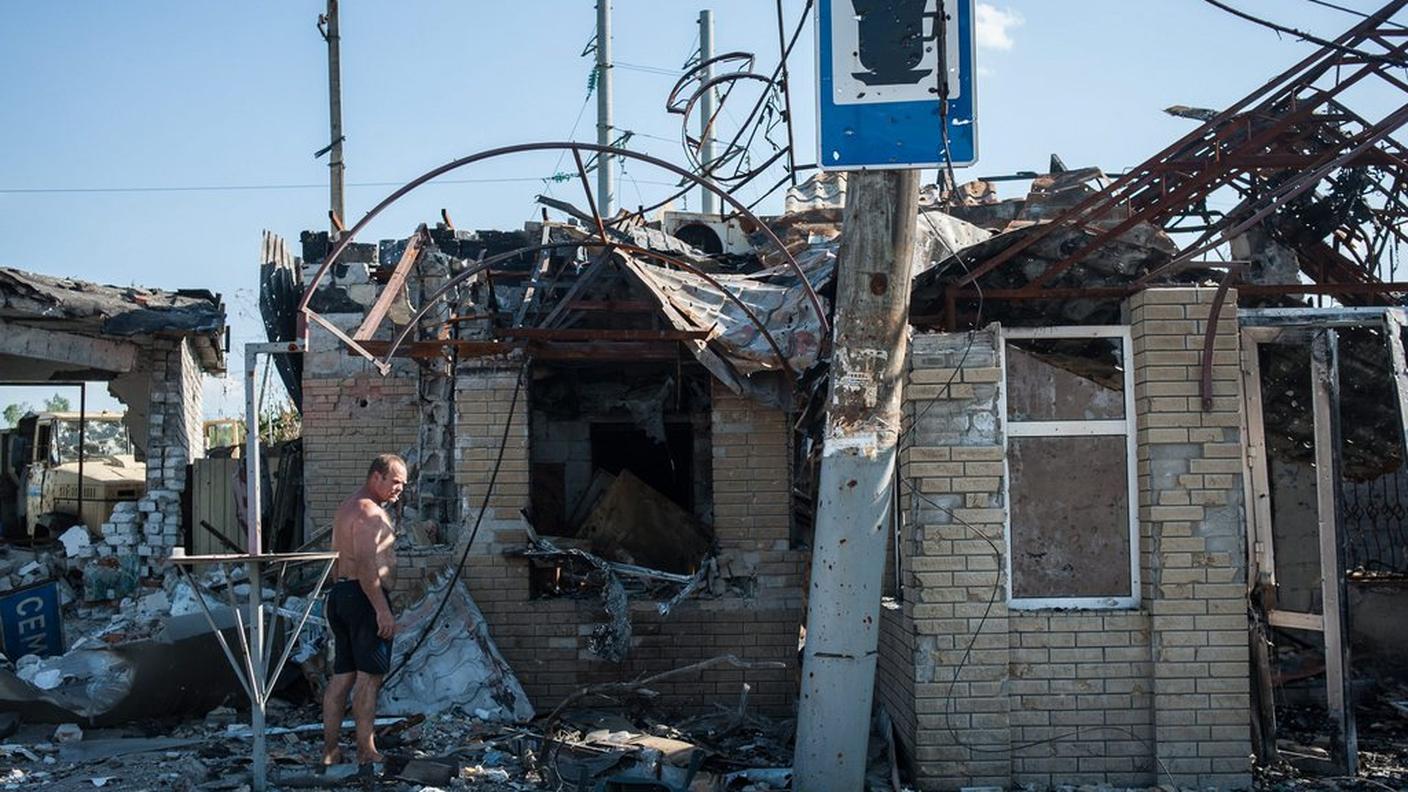 Un uomo guarda quel che resta di una casa nell'est dell'Ucraina 