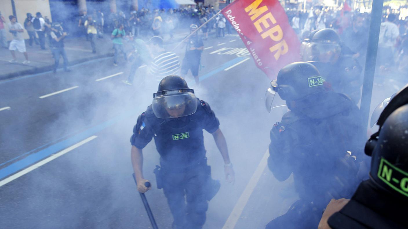 Poliziotti si liberano di un lacrimogeno presso lo stadio Maracanà