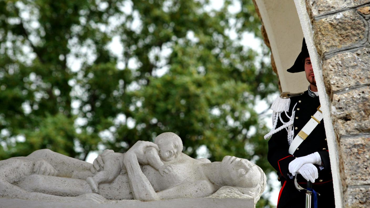 Un carabiniere di guardia vicino a un monumento ai caduti dell'eccidio