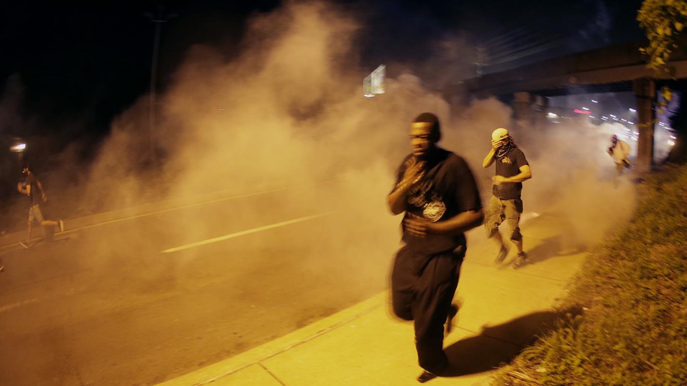 La fuga da una strada di Ferguson dopo il lancio di lacrimogeni
