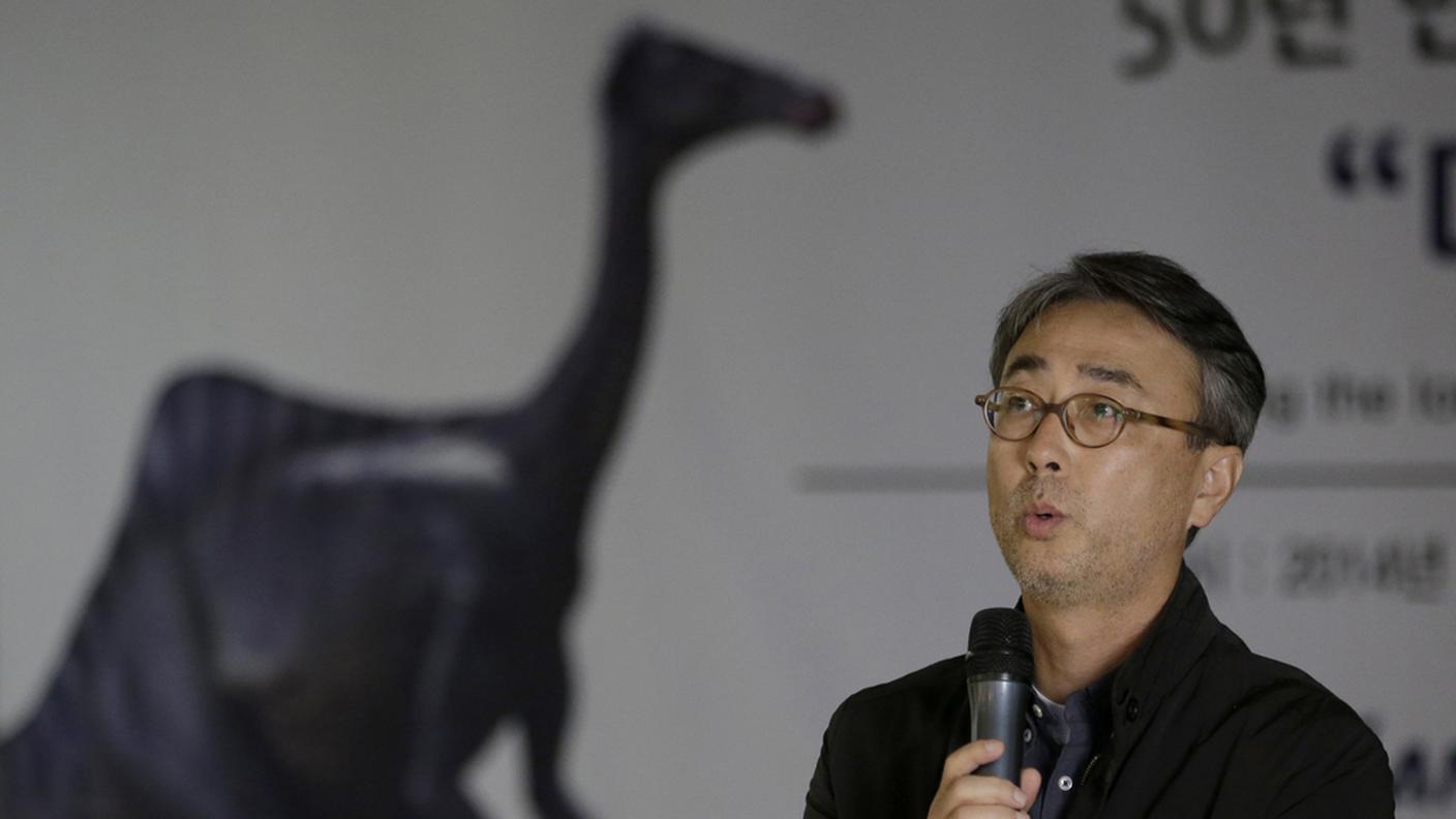 Il direttore del museo geologico di Daejeon, Yuong-Nam Lee. Sullo sfondo il profilo del dinosauro