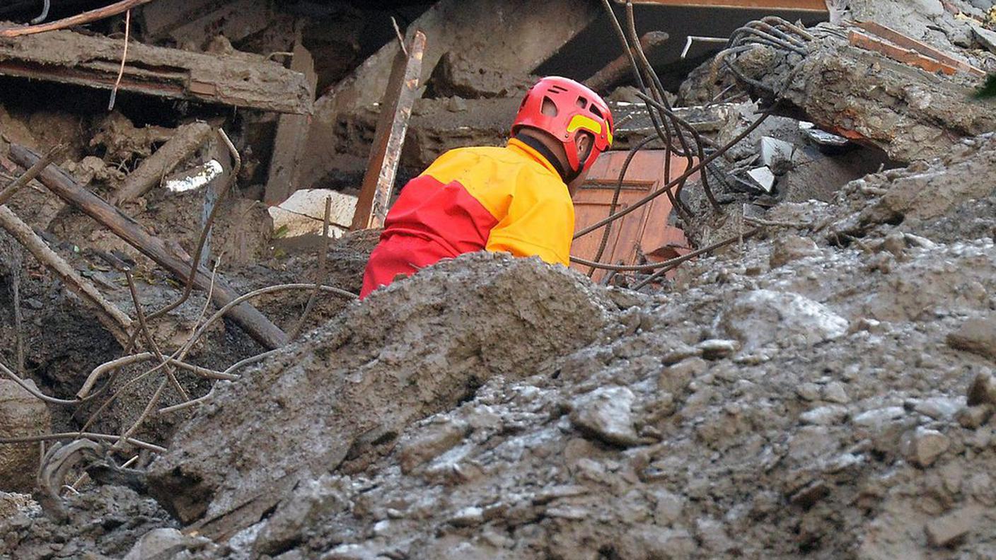 Un soccorritore tra le macerie di una casa