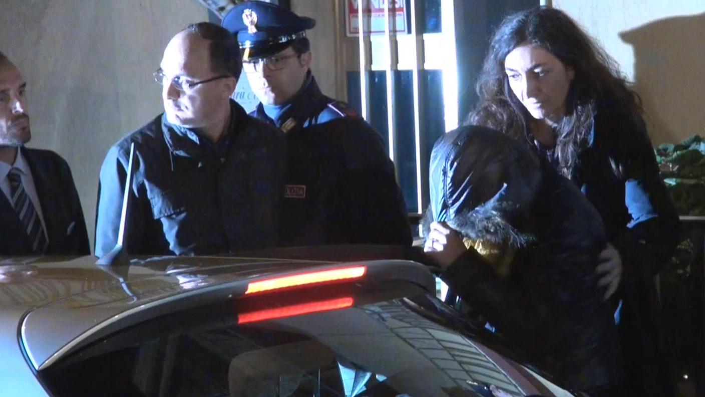 La donna mentre si copre il volto con un cappuccio, prima del trasferimento in procura