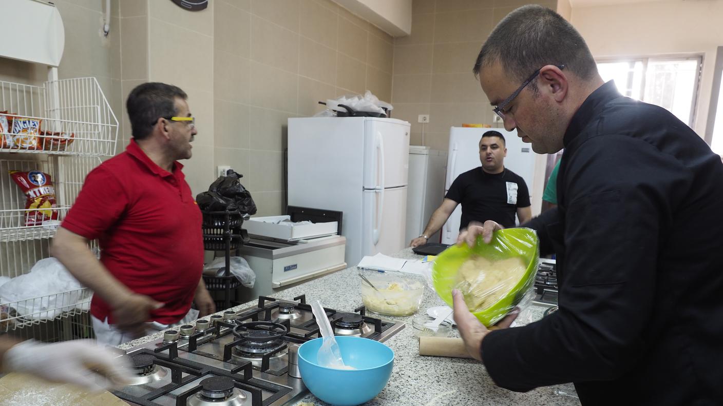 Lo chef Luigi Oriente al lavoro, in cucina, con i suoi apprendisti