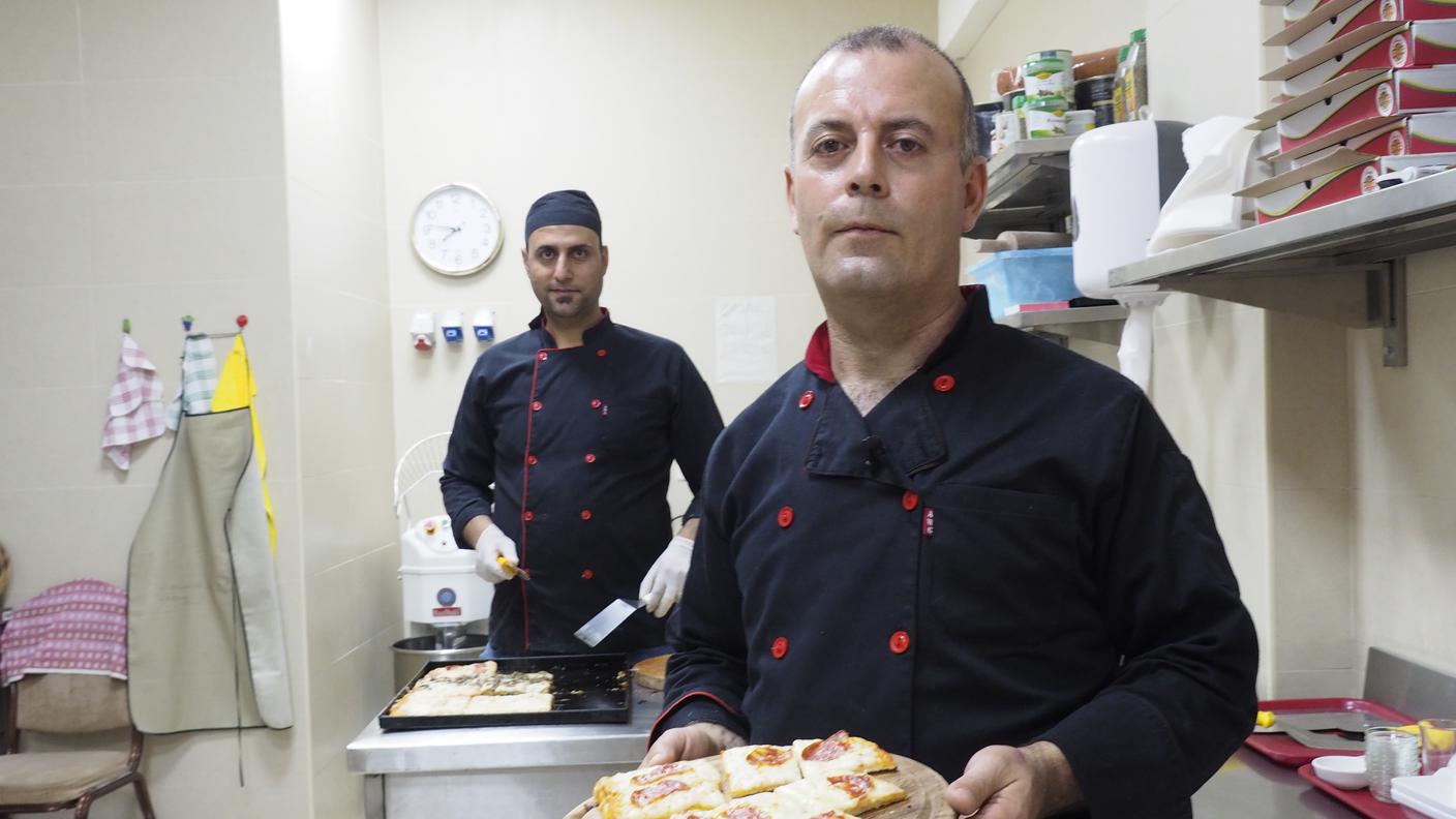 I due pizzaioli iracheni hanno appena sfornato e tagliato la pizza