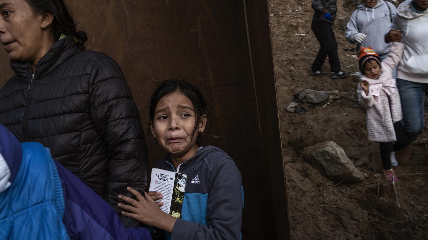Fergie (9, Guatemala) piange spaventata mentre con sua madre e altri migranti cercano di attraversare il muro di confine tra il Messico-US, Tijuana, Dicembre 2018
