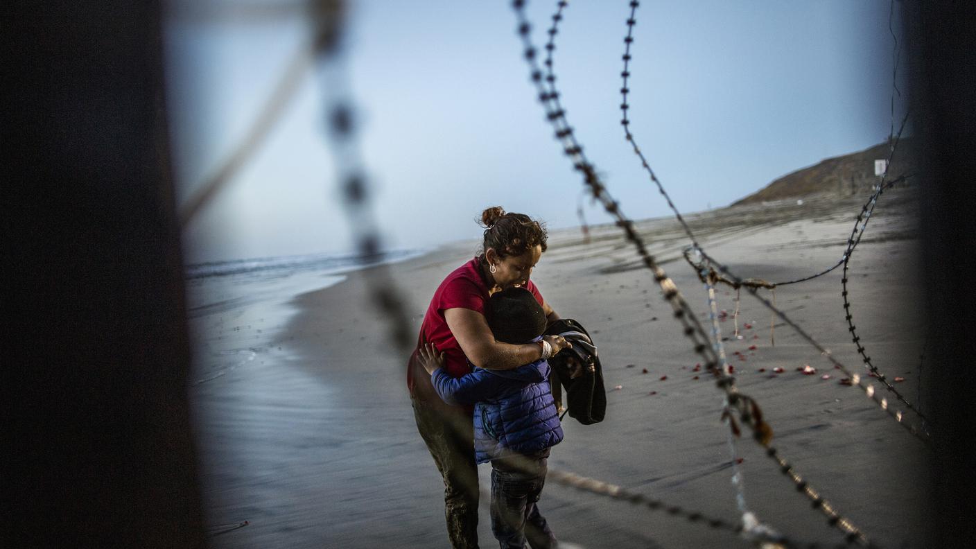 Una donna abbraccia il suo bambino dopo aver attraversato illegalmente il muro di confine tra Messico-US, Tijuana, Dicembre 2018