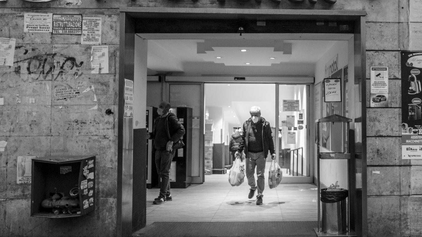 Un uomo esce dal supermercato con ingresso contingentato