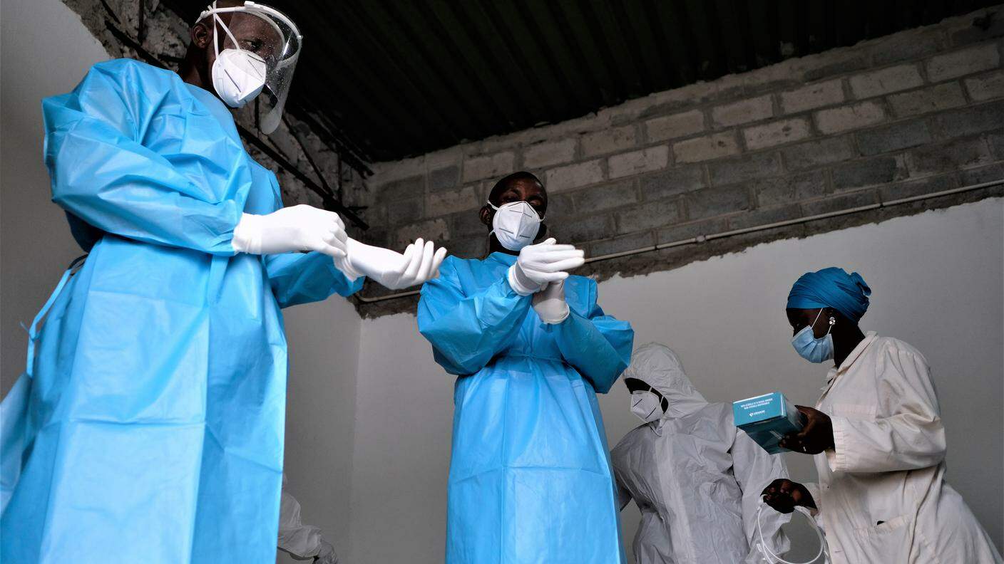 Due medici guineani si preparano nella stanza sterile prima di entrare nel reparto Covid-19