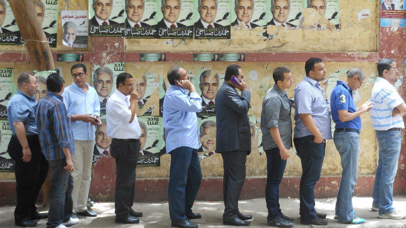 Uomini al voto nelle prime elezioni presidenziali libere in Egitto nel 2012. Sullo sfondo manifesti del leader di sinistra Hamdin Sabahi