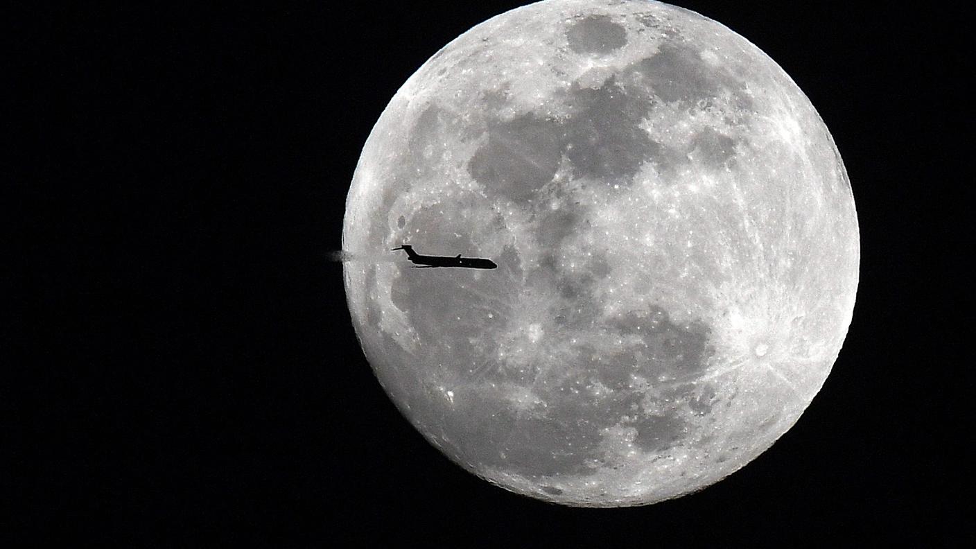 Un aereo passa davanti alla "superluna" piena, iniziata la scorsa notte