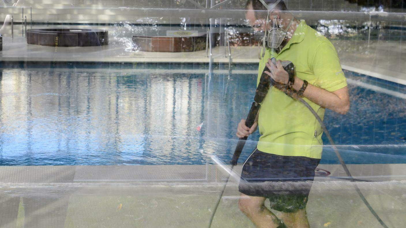 Un dipendente della piscina, impegnato nelle pulizie con una maschera protettiva