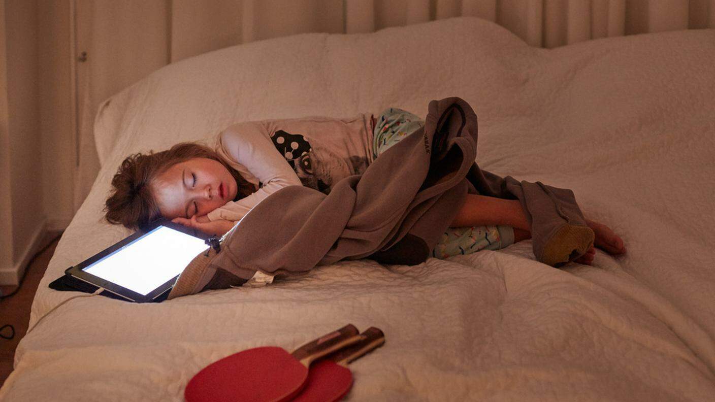 Una bambina dorme con un tablet accceso