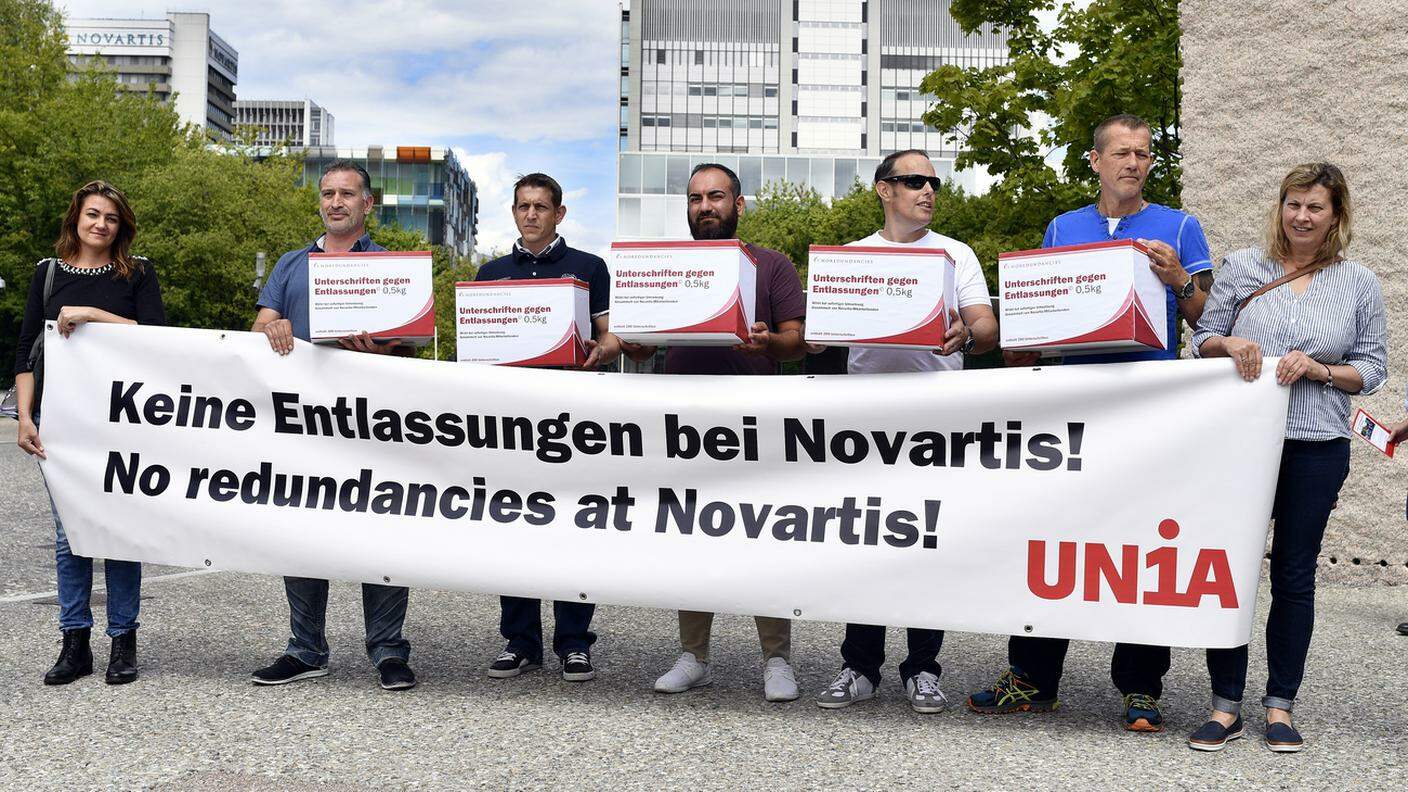 Manifestanti con uno striscione presso la sede della Novartis a Basilea