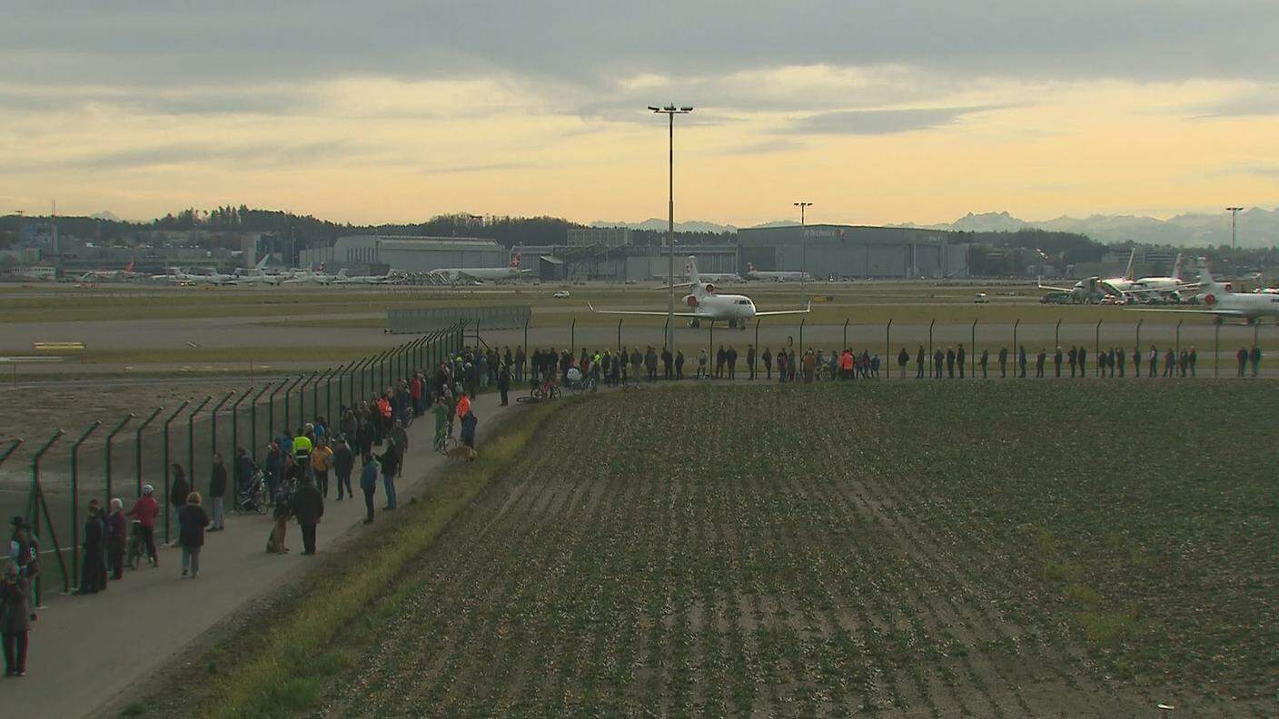 I curiosi riuniti alla recinzione dell'aeroporto per assistere all'arrivo di Trump