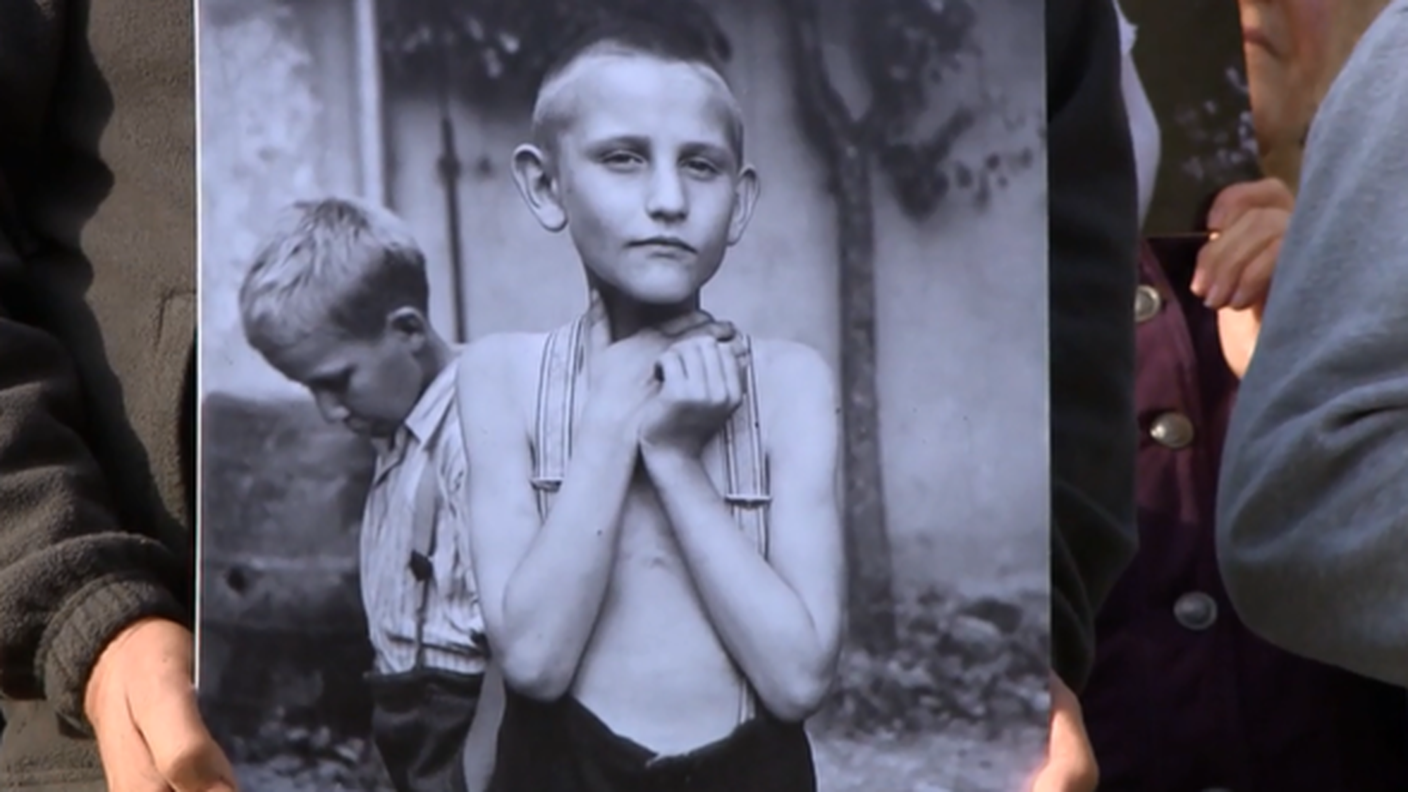 Una vittima di collocamento coatto mostra una sua foto
