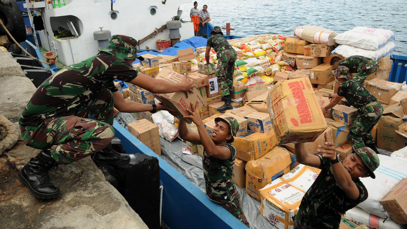 I soldati indonesiani scaricano pacchetti di donazioni da una nave a Palu