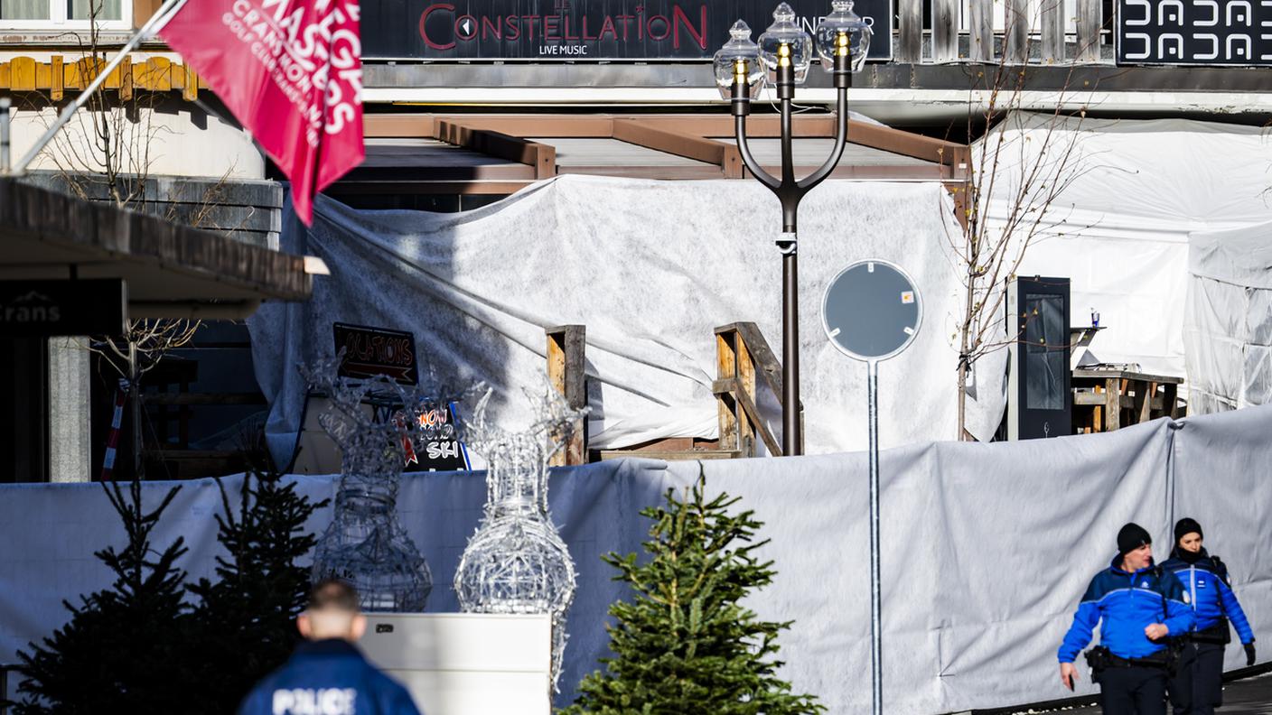 Agenti di polizia all'esterno del bar "Le Constellation", dove è scoppiato l'incendio: l'area è stata coperta da teli