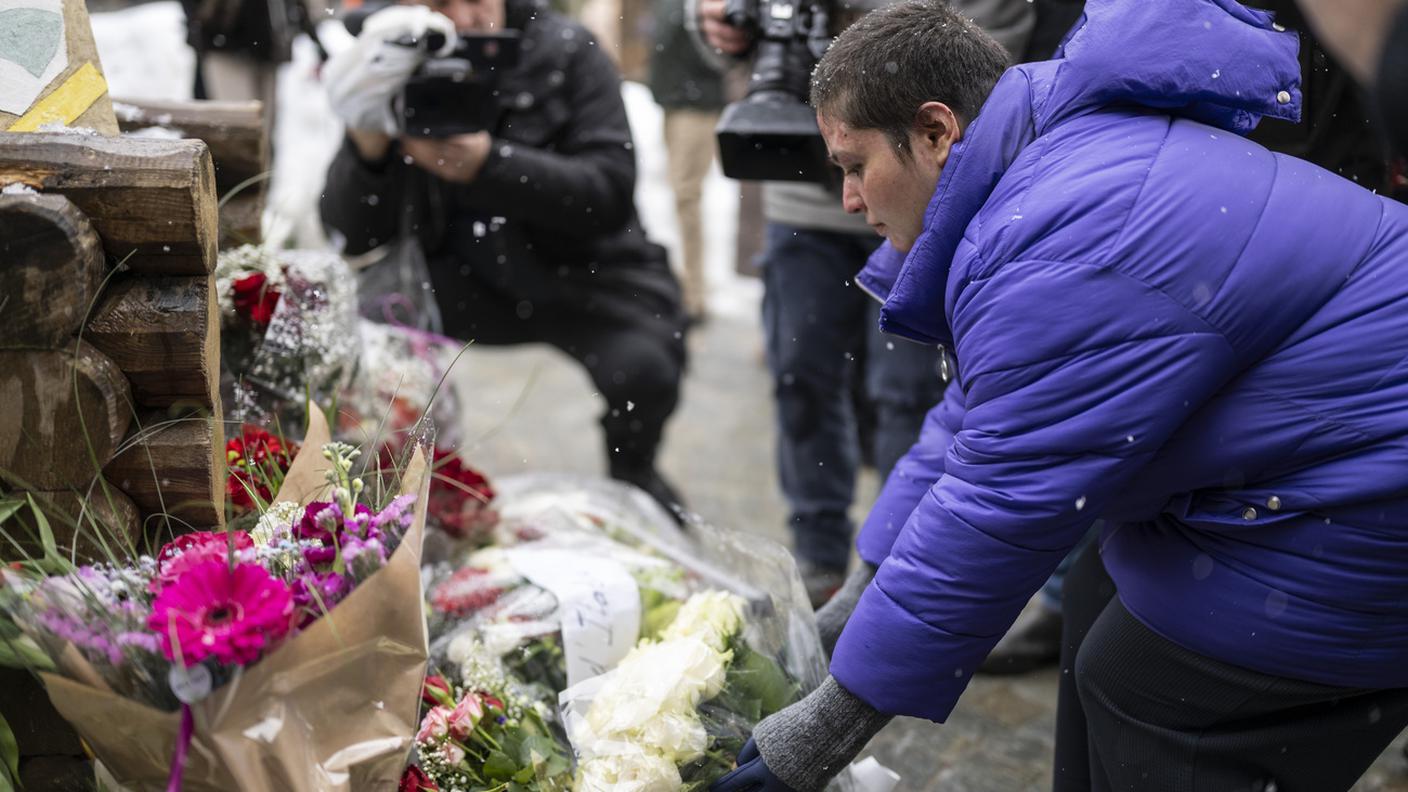 Roze deposita dei fiori per commemorare le vittime dell'incendio del bar "Le Constellation"