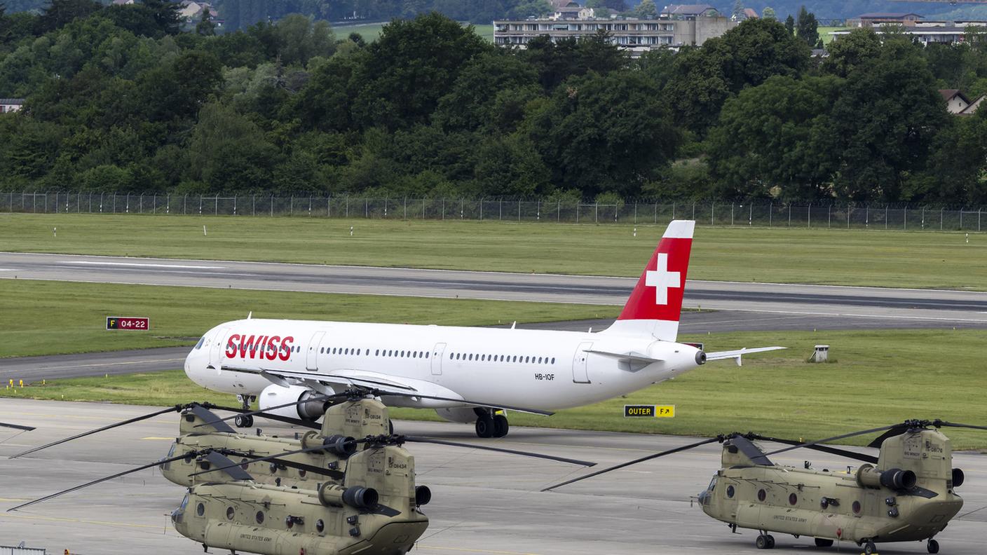 Un aereo della Swiss passa accanto ad elicotteri Chinook statunitensi: è all'aeroporto di Ginevra che è atteso l'arrivo dei leader del G7, compreso il presidente statunitense Donald Trump