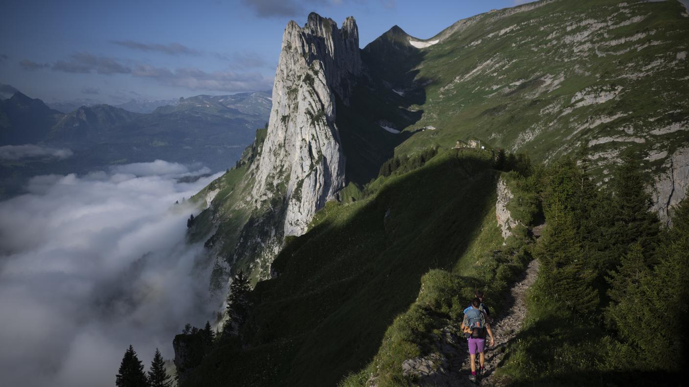 Degli escursionisti percorrono un sentiero con vista sulle Kreuzberge e su alcuni campeggiatori non autorizzati, lunedì 29 luglio 2024, nella regione dell'Alpstein, nei pressi di Brülisau. Nell'Alpstein il campeggio libero è vietato.
