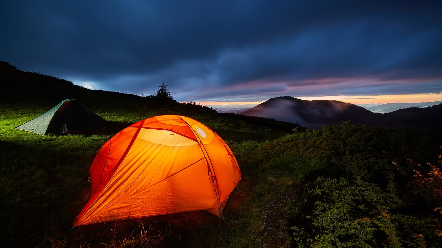 Tenda da campeggio illuminata durante una notte di luna piena.