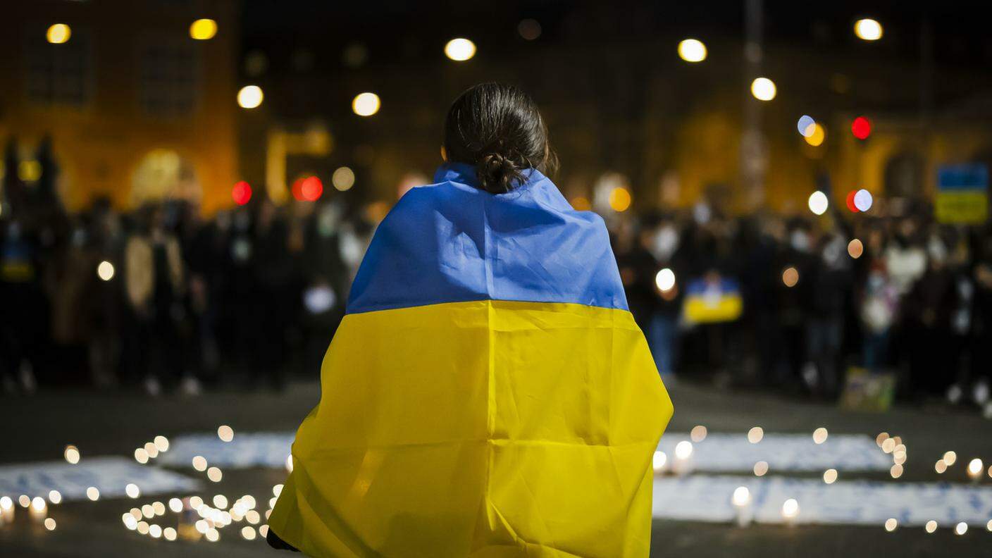 Una donna ammantata dalla bandiera ucraina, durante la dimostrazione che si è svolta in serata a Zurigo