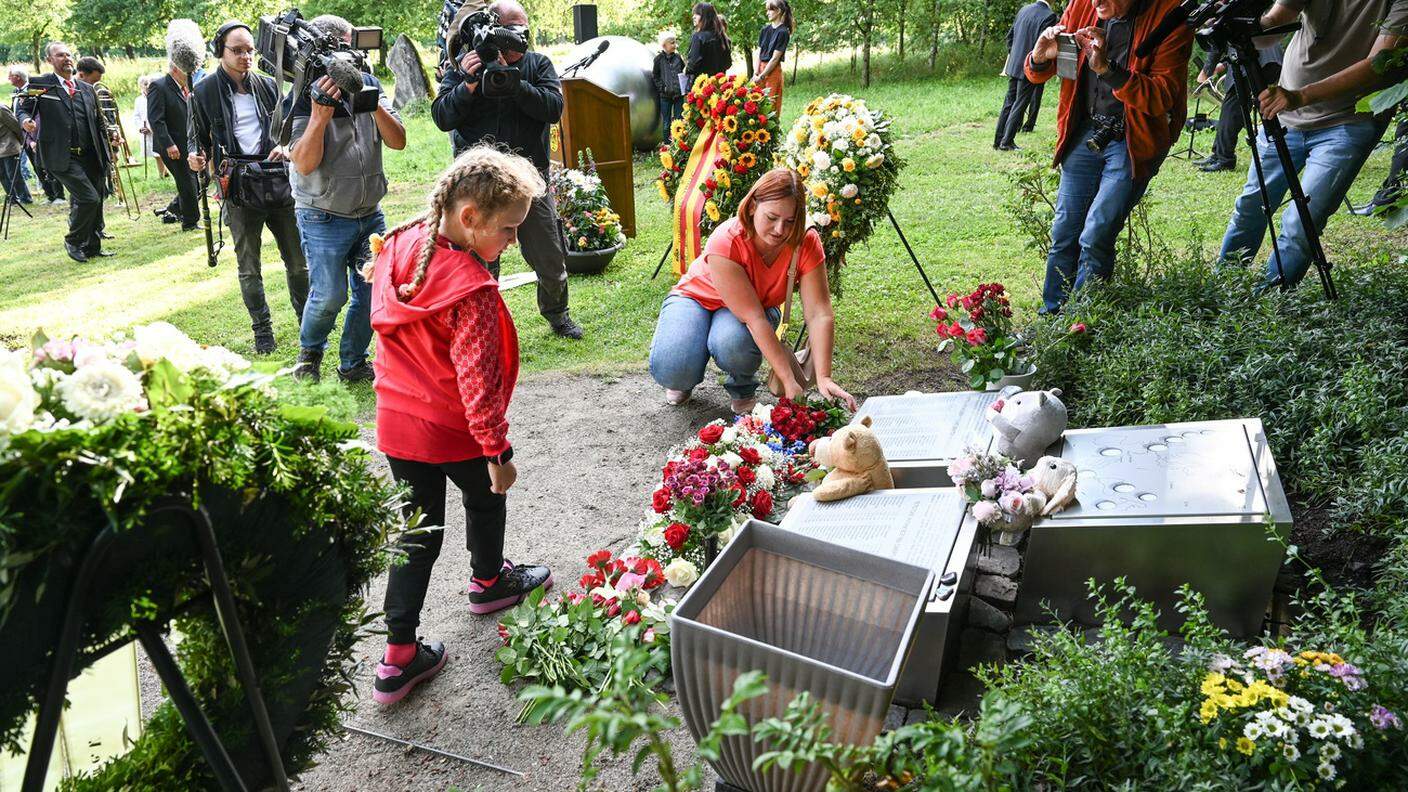 La sorella di una delle vittime russe, con la figlia, depone dei fiori al monumento in memoria delle vittime