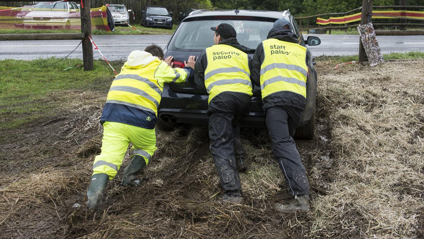 Addetti dello staff liberano un'auto rimasta impantanata nel fango a seguito delle intense piogge