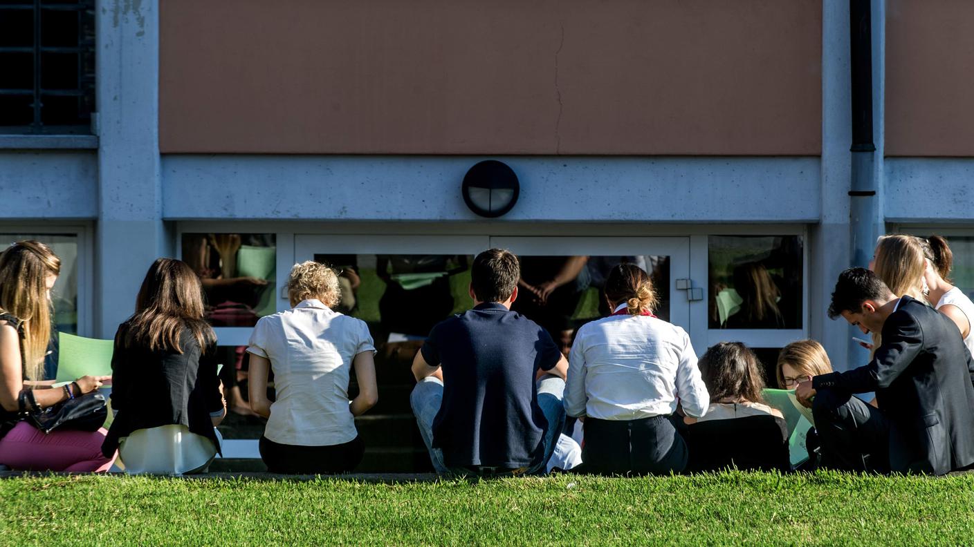 Studenti attendono l'inizio delle lezioni davanti a un istituto scolastico