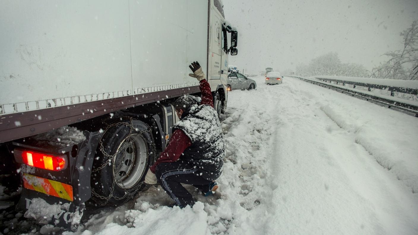 Un camionista bloccato sull'autostrada A2 tenta di montare le catene