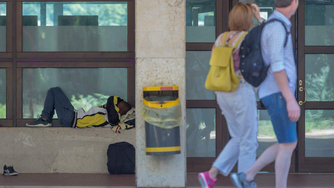Turisti osservano un migrante in stazione